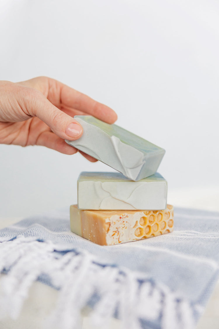 Cold Process Soap Made in Alaska. Bar soap stacked on a blue and white towel.