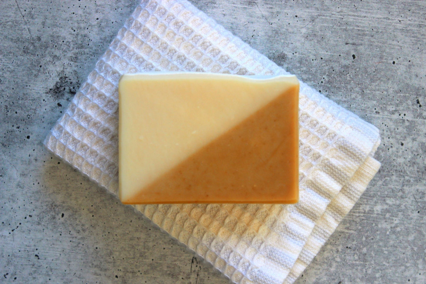 Bar of soap on a striped towel with a concrete surface background