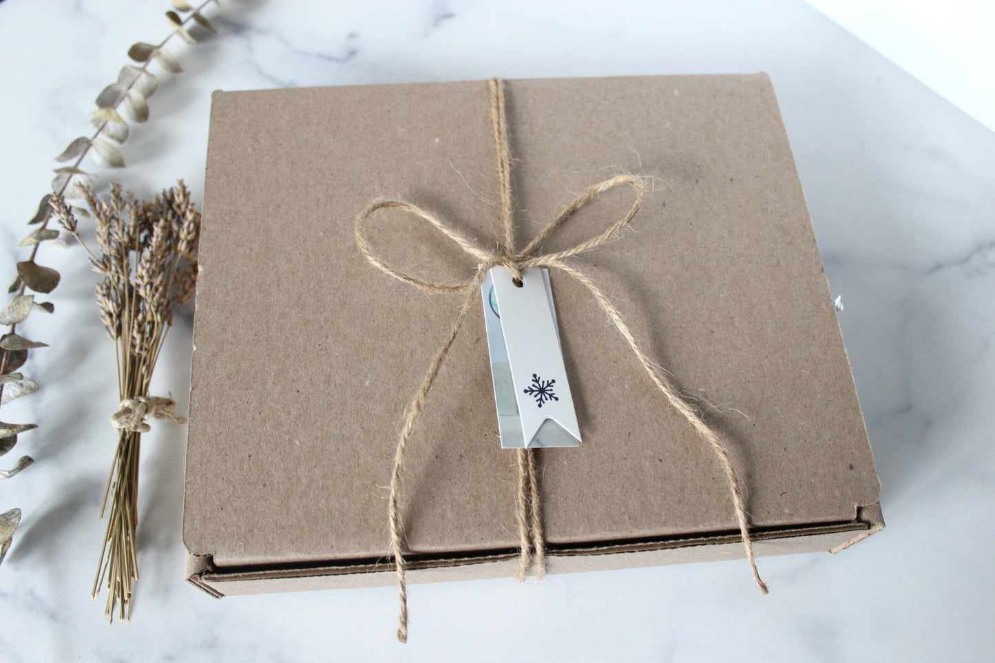 Brown paper box with string and tag on a marble surface