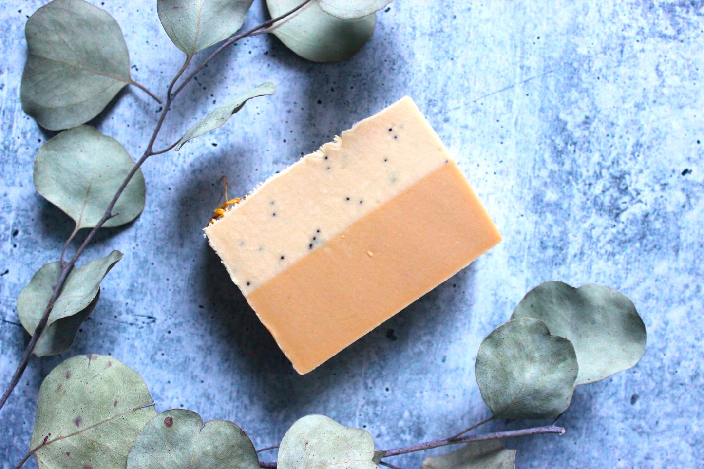 Lemon Goat Milk Soap surrounded by dried eucalyptus leaves.