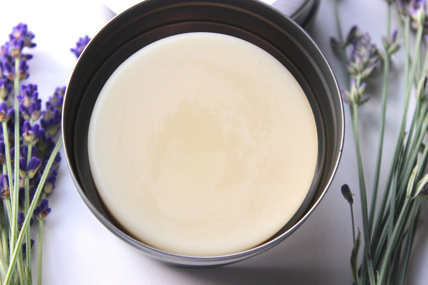 Mango Butter Lotion Bar in tin. Dried lavender rest around tin.