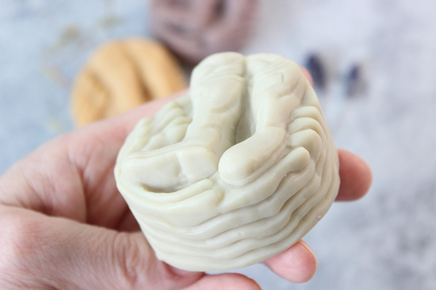 Alaskan Seaside Soap, in green color, held in a hand. Soap is shaped like boots.