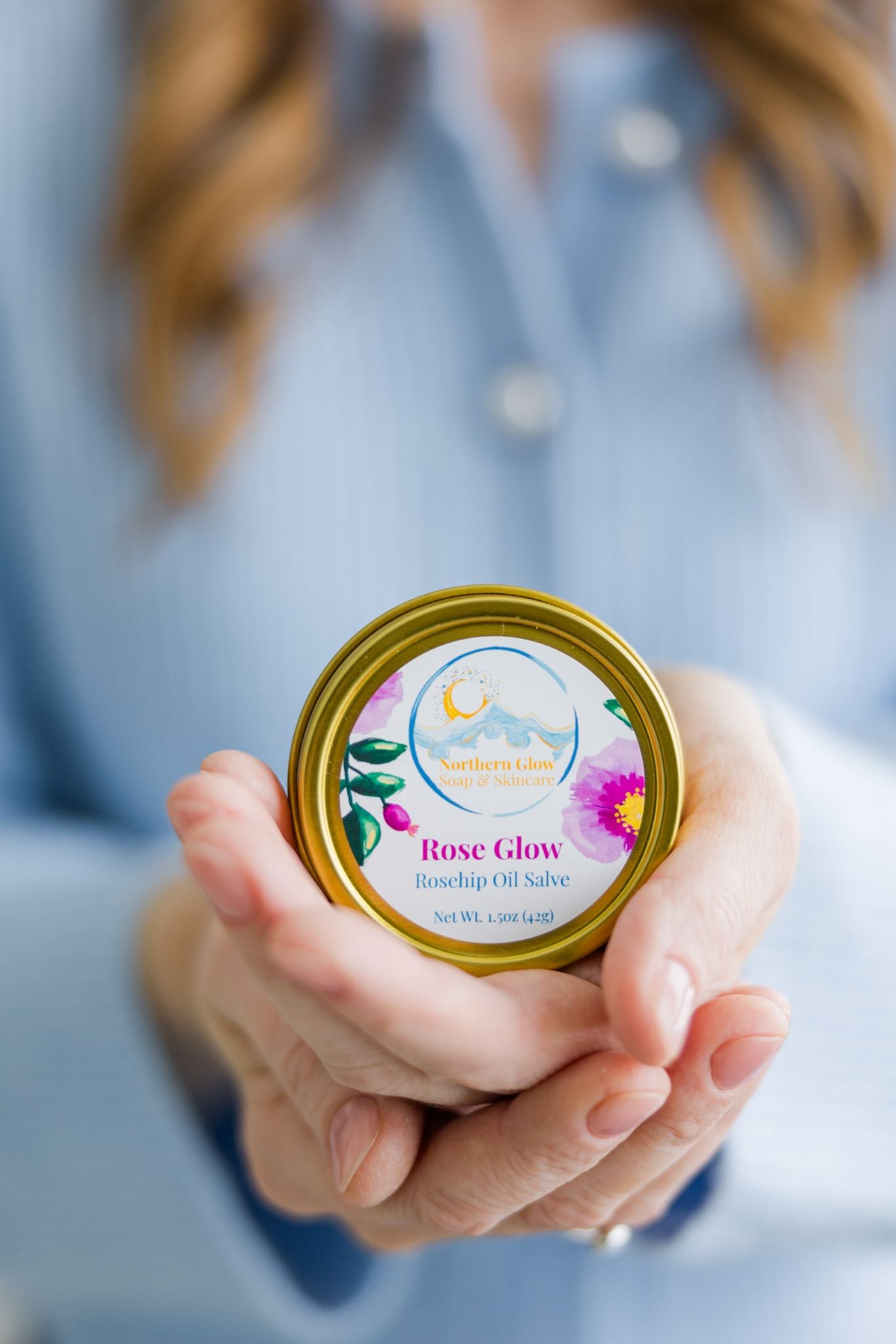 Apricot Oil and Beeswax Salve in Rose Glow held in a woman's hands.