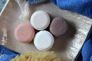 Aromatherapy shower steamers tablets on a ceramic soap dish.