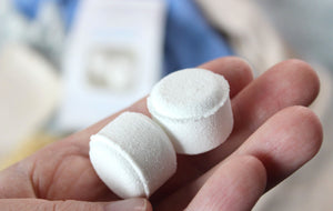 Aromatherapy shower steamers tablets held in a hand.