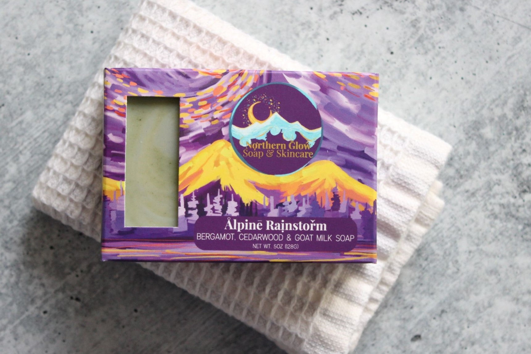 Bergamot soap in a purple box, sitting on a white washcloth.