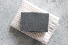 Load image into Gallery viewer, Charcoal coffee soap on a white washcloth.
