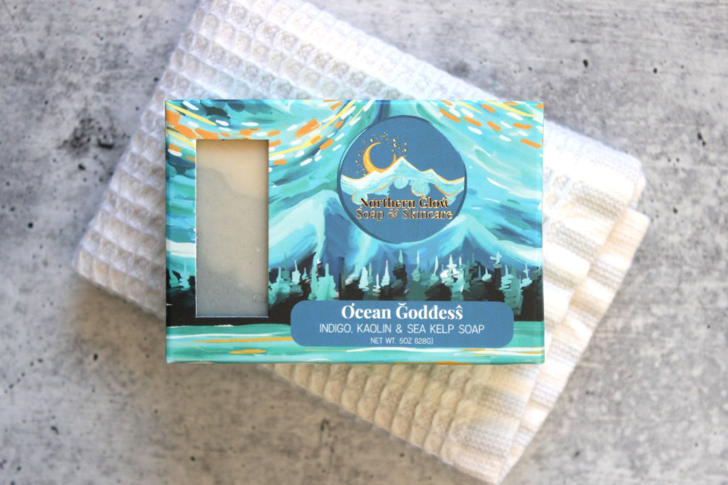 Ocean Goddess soap in a blue box, sitting on a white washcloth.
