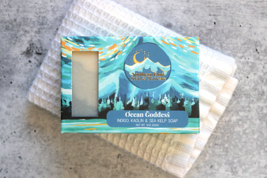 Ocean Goddess soap in a blue box, sitting on a white washcloth.
