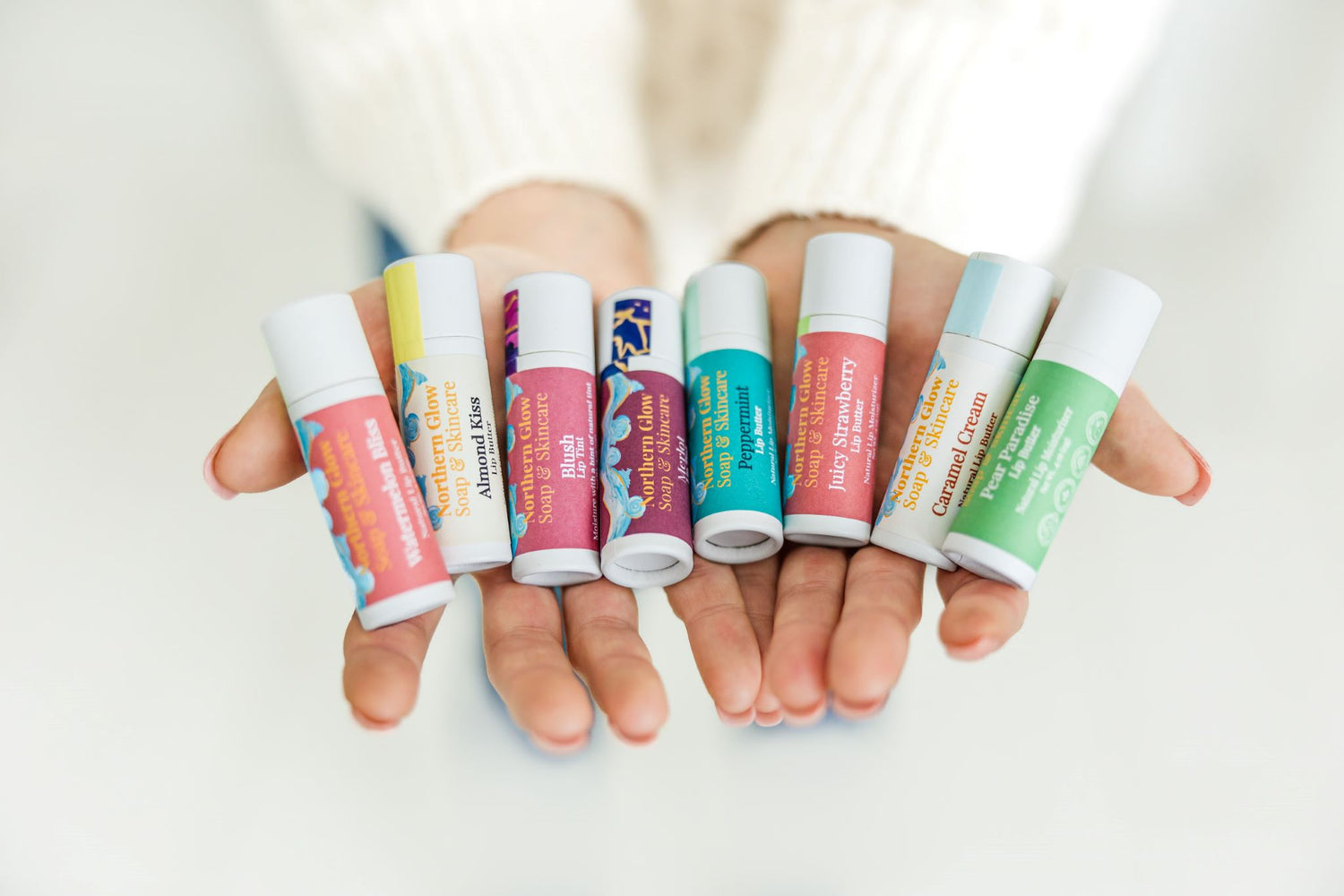 A woman holding natural lip balms in her hands.