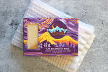 Load image into Gallery viewer, Eucalyptus soap with sea kelp and matcha in a purple box, on a white washcloth.
