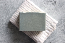 Load image into Gallery viewer, Fir needle, lime and goat milk soap on a white washcloth.
