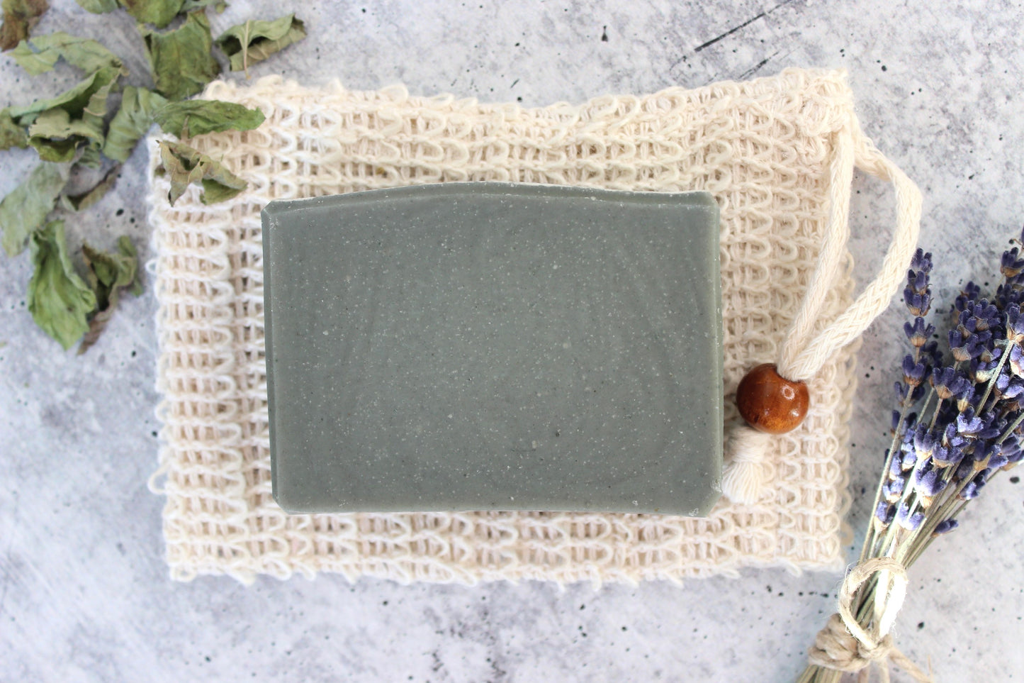 Fir needle and goat milk soap on a soap saver bag, with dried flowers and herbs.