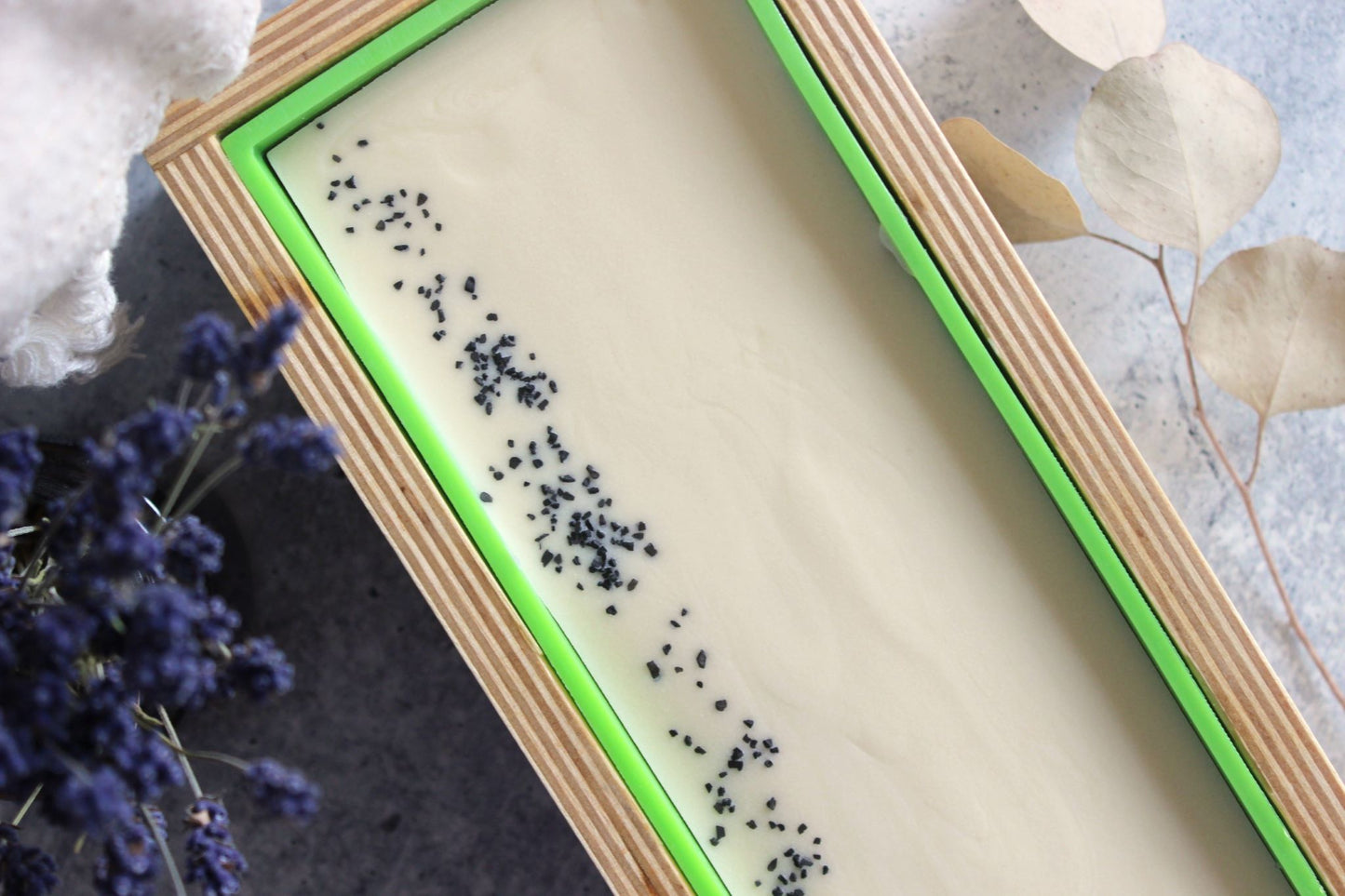 Glacier Breeze soap in a wooden soap mold. Dried lavender flowers are placed next to the soap mold.