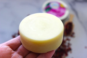 Jojoba oil and shea butter lotion bar held in a hand.