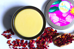 Jojoba oil and shea butter lotion bar in a silver tin.  Dried rose petals surround the tin.