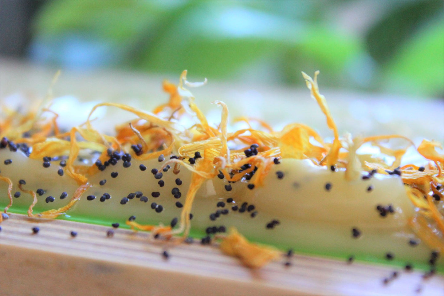 Lemon scrub bar soap topped with poppy seeds and dried calendula flowers.