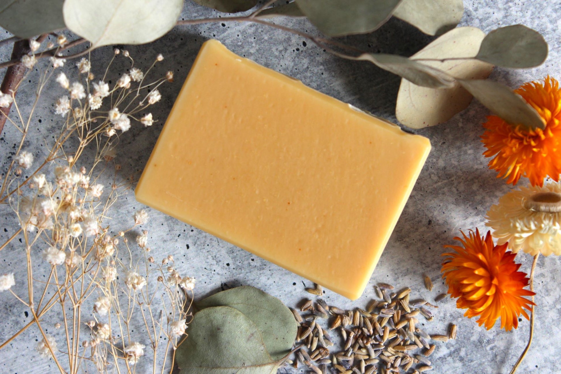 Golden yellow turmeric soap is surrounded by dried floral.