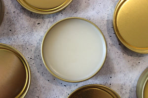 Natural salves with beeswax and vitamin e oil in a golden tin.