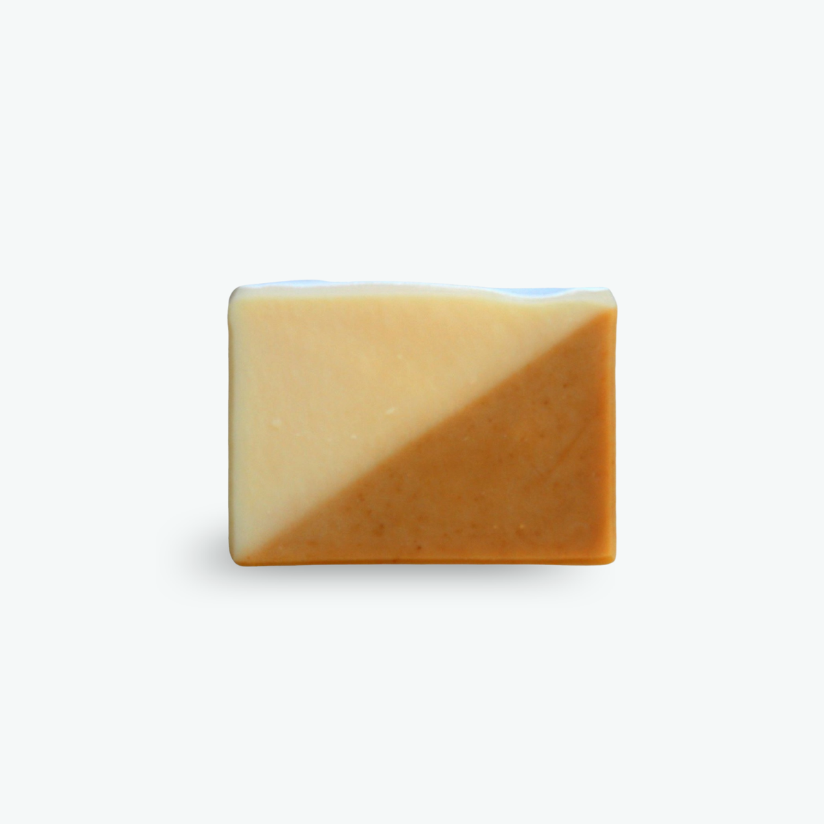 A rectangular bar of soap with a diagonal split design, featuring a light cream top half and a warm caramel-brown bottom half, set against a plain white background.