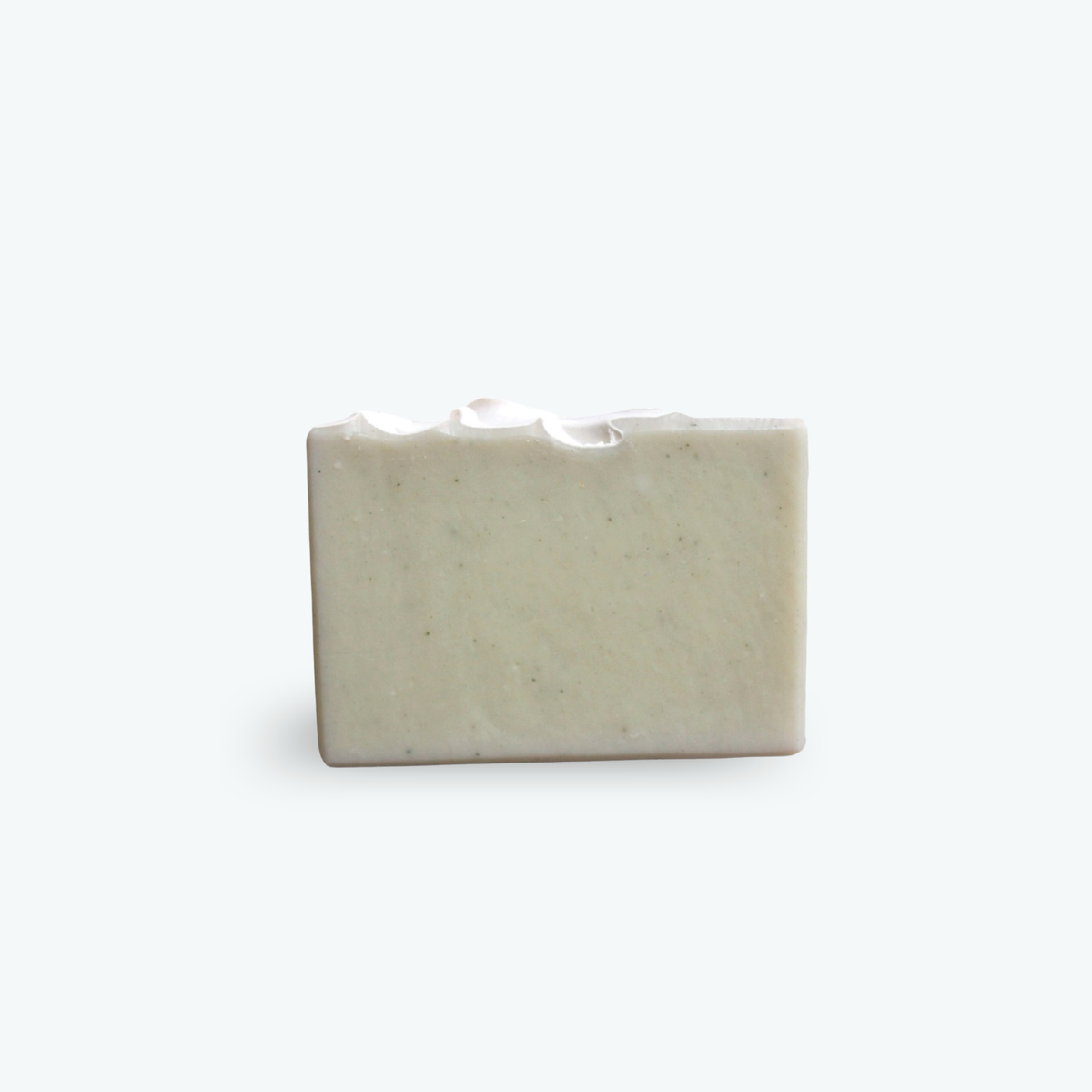 A rectangular bar of handmade soap with a textured, speckled surface and a wavy cut detail along the top edge, shown on a clean white background.