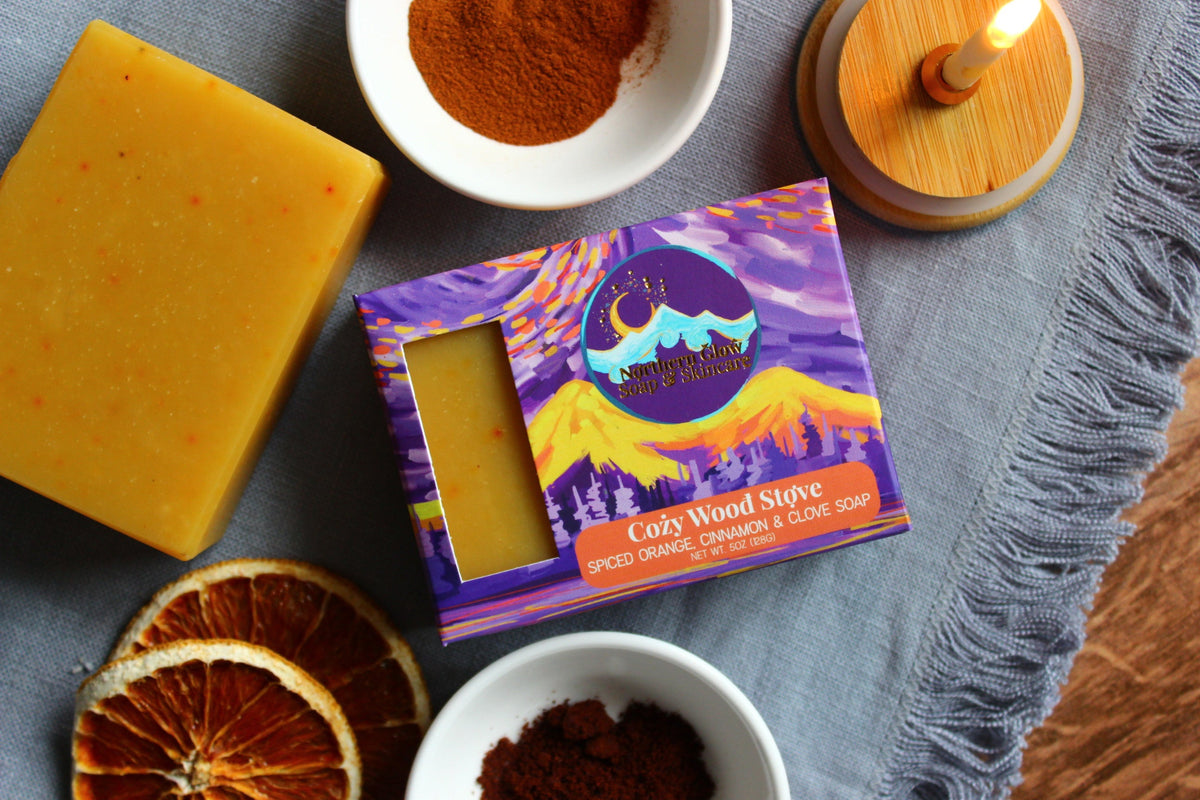 Northern Glow Soap Spicy Orange and Clove Bar Soap next to white bowls of spices and a burning candle.