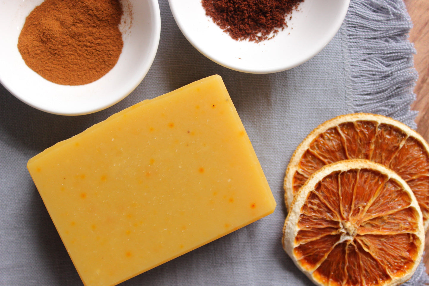 Northern Glow Soap Spicy Orange and Clove Bar Soap next to dried oranges and cinnamon and clove spices.