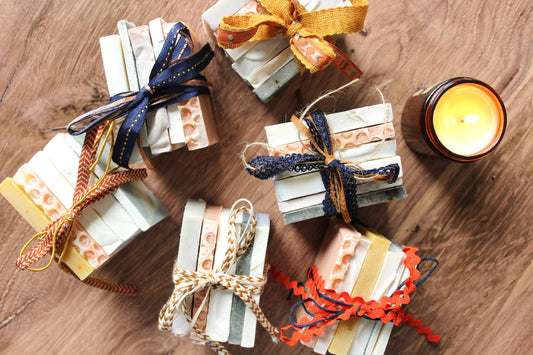 Bundles of soap ends are wrapped in fall themed ribbon, next to the glow of a candle.