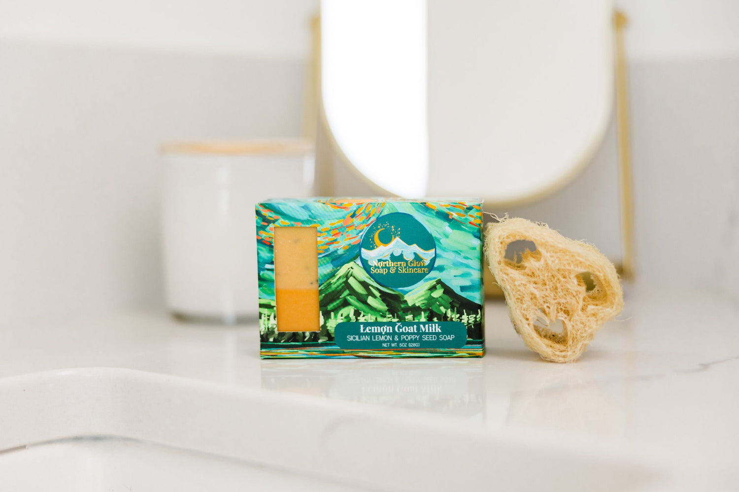 Lemon Goat Milk soap in a green box next to a natural loofa.
