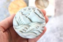 Load image into Gallery viewer, Alaskan Seaside soap, shaped as mountains.  Soap is blue and held in a hand.
