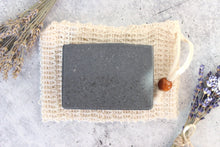 Load image into Gallery viewer, Charcoal Coffee Soap on a cambric soap saver pouch.  Dried lavender in background.
